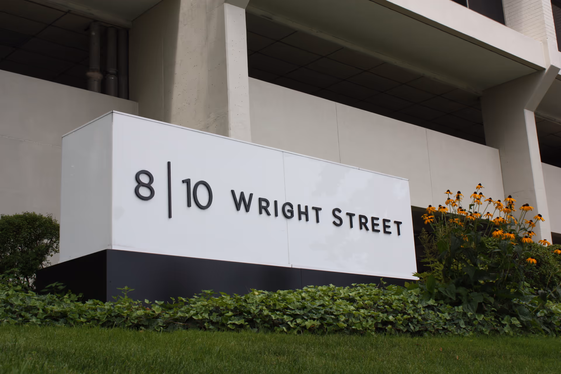 Front view of a building with a white sign reading 8 10 Wright Street and landscaping.