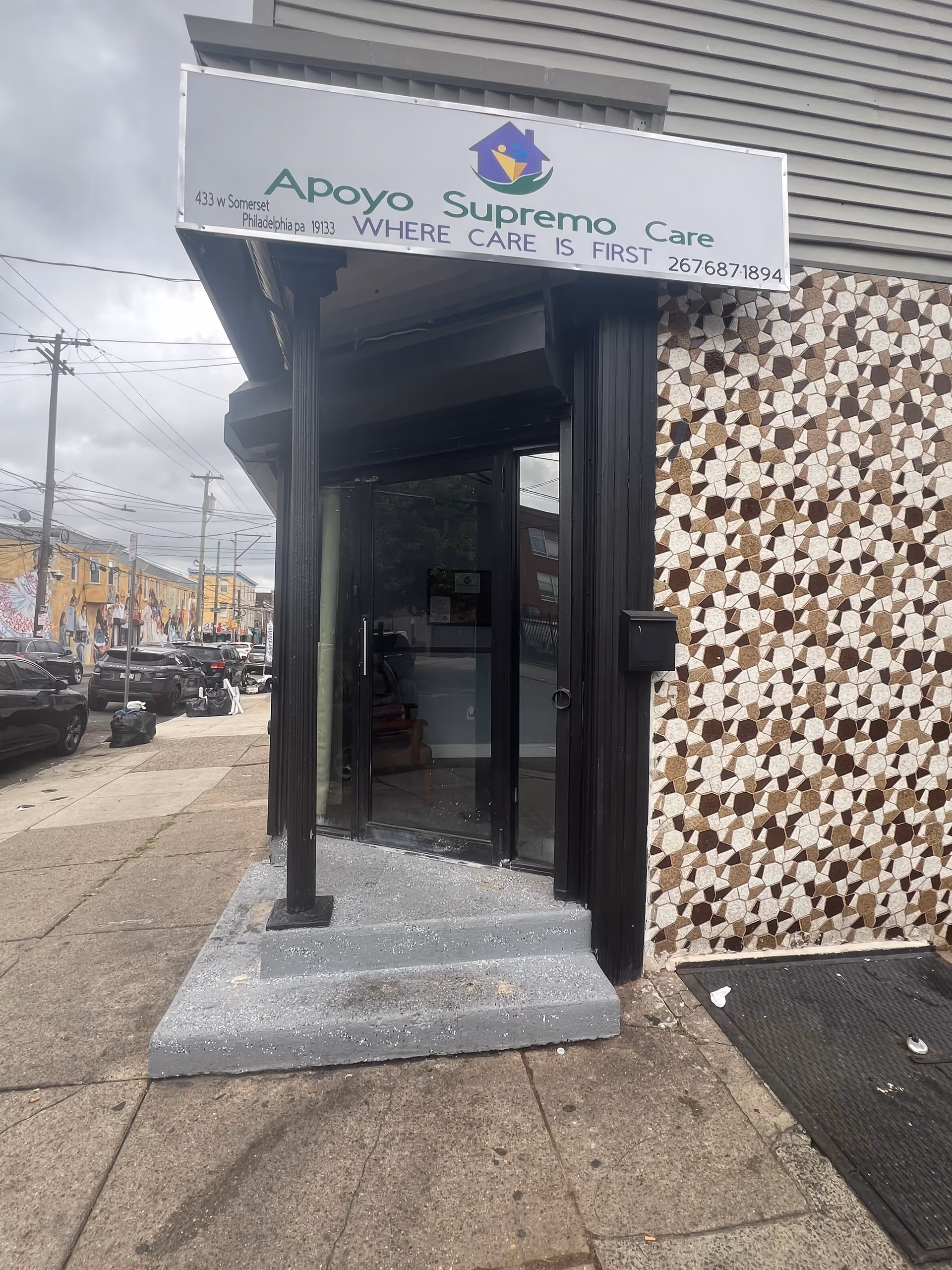 Exterior view of Apoyo Supremo Care entrance with a sign and patterned wall.