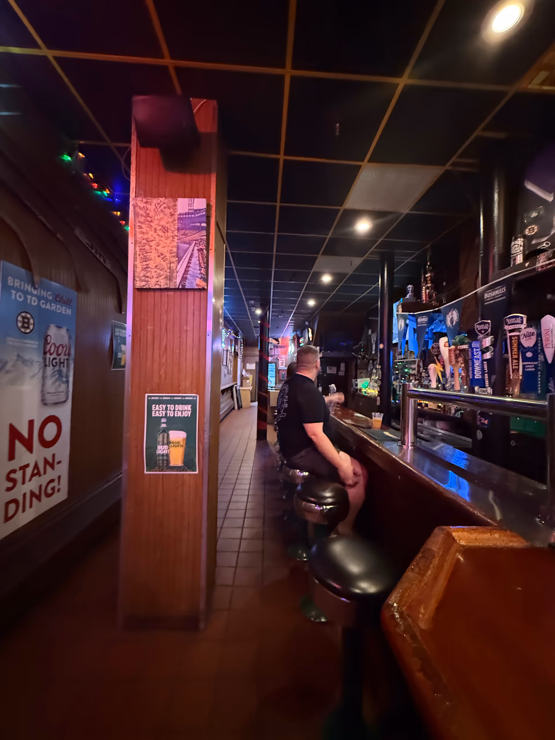 Dim bar interior with a long counter, stools, and neon lights in a facility.
