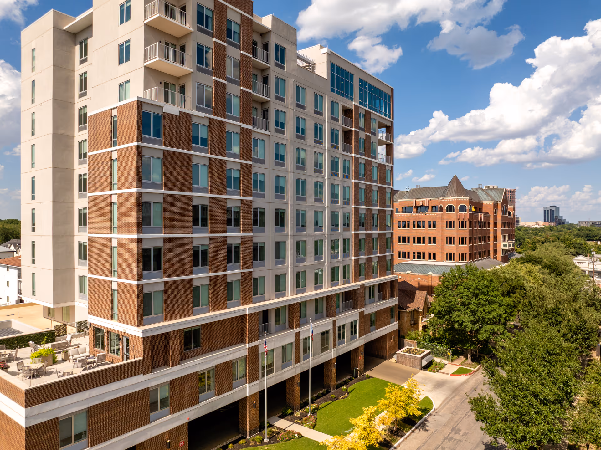 Exterior view of Anthology of Highland Park, a multi-story senior building with brick and beige façade.