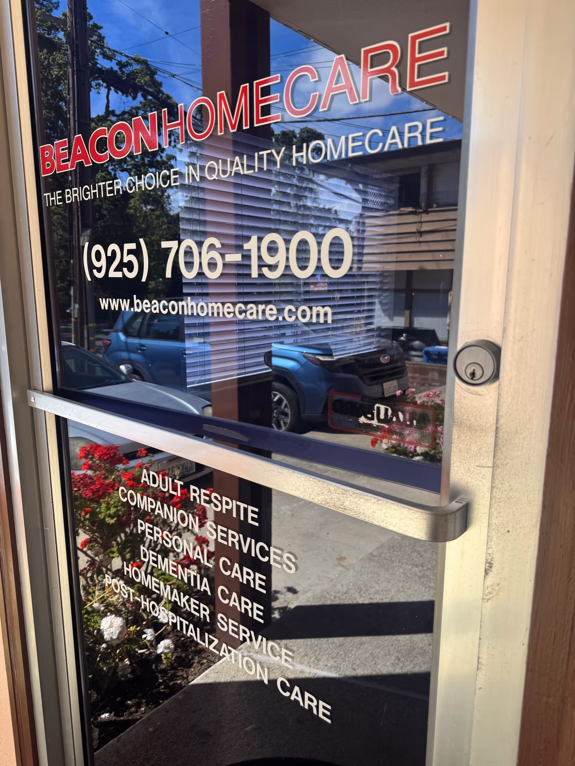 Front glass door of Beacon Home Care with large sign, phone number, and website.