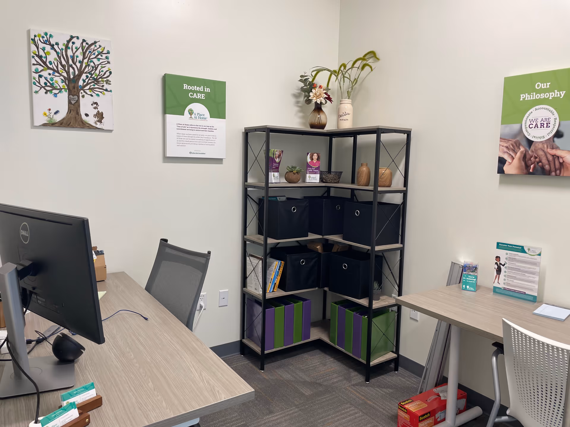 Interior office area of a senior living facility with desk, computer, shelving, and posters.