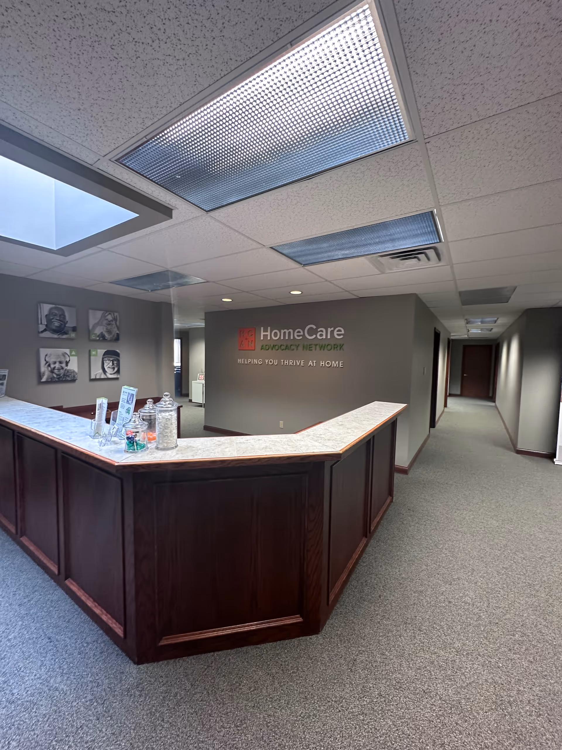 Dark wood reception desk in a grey lobby with a HomeCare Advocacy Network Omaha sign.