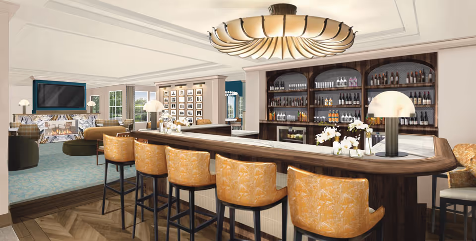 Elegant hotel-style bar area with amber stools, dark wood bar, and beverage shelves.