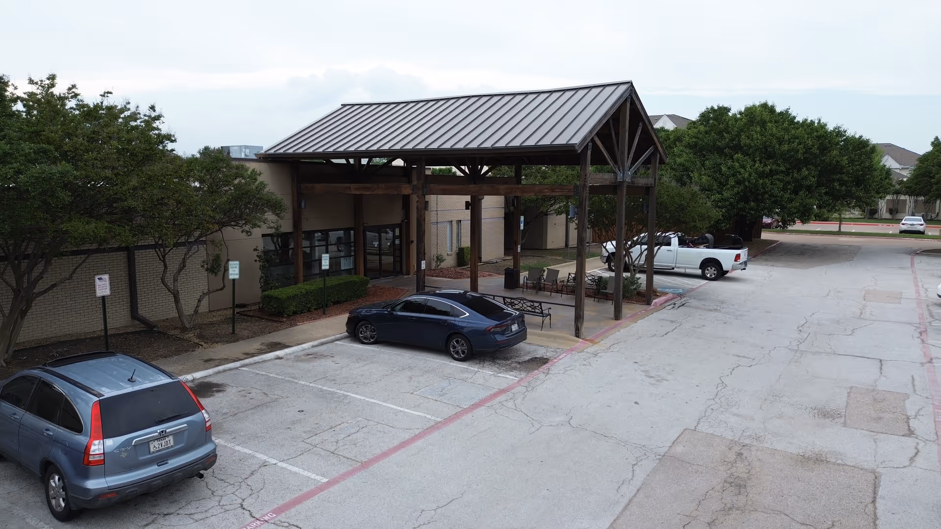 Exterior view of Brookhaven Nursing and Rehabilitation Center entrance with a wooden canopy and parked cars.