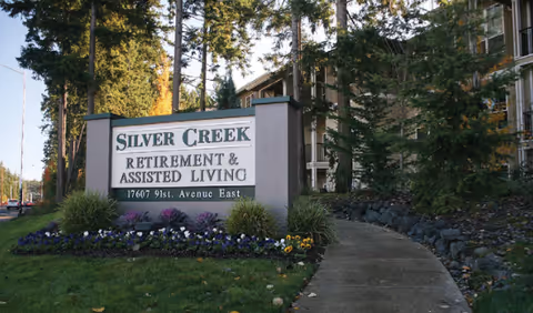 Exterior view of Silver Creek Retirement & Assisted Living entrance sign with a curved sidewalk.