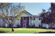 Park Place Assisted Living building with green lawn, trees, and a front entrance.