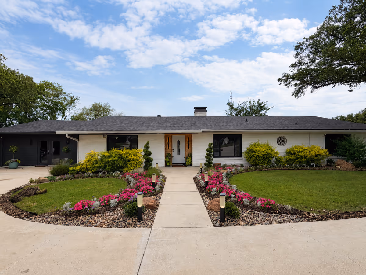 Front view of a single-story senior living facility with landscaped entrance and walkway.