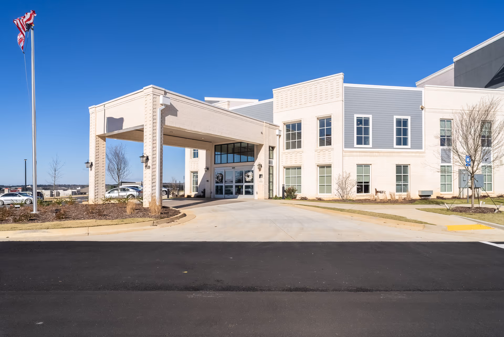 Modern two-story medical facility with a covered entrance and American flag in daylight at the front.