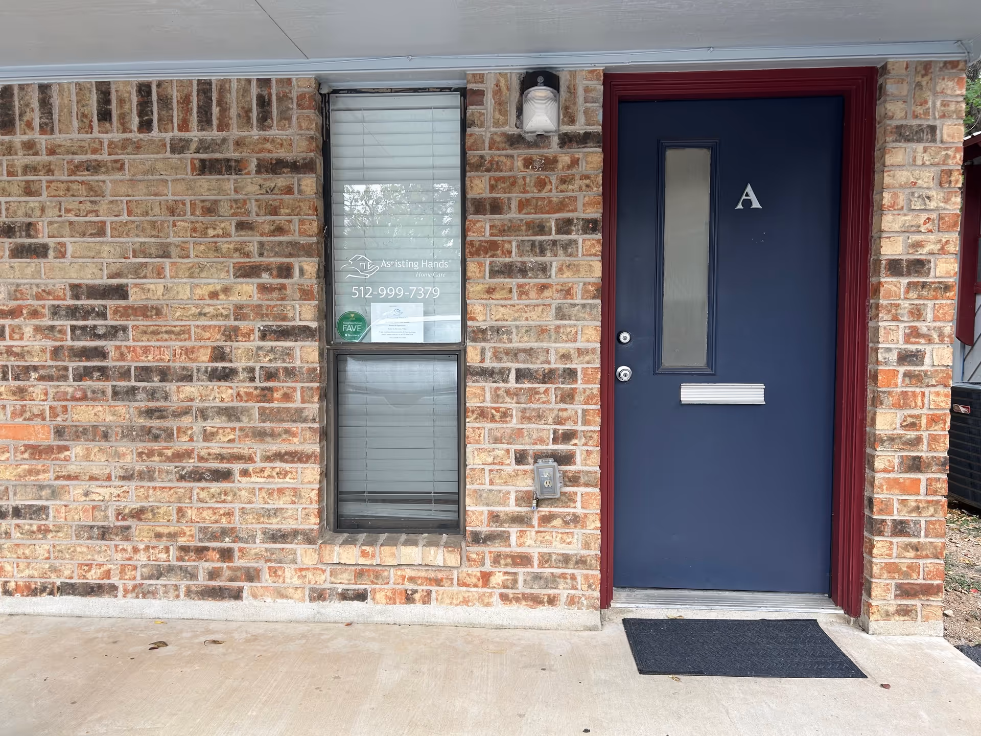 Brick exterior of Assisting Hands facility with a blue front door labeled A.