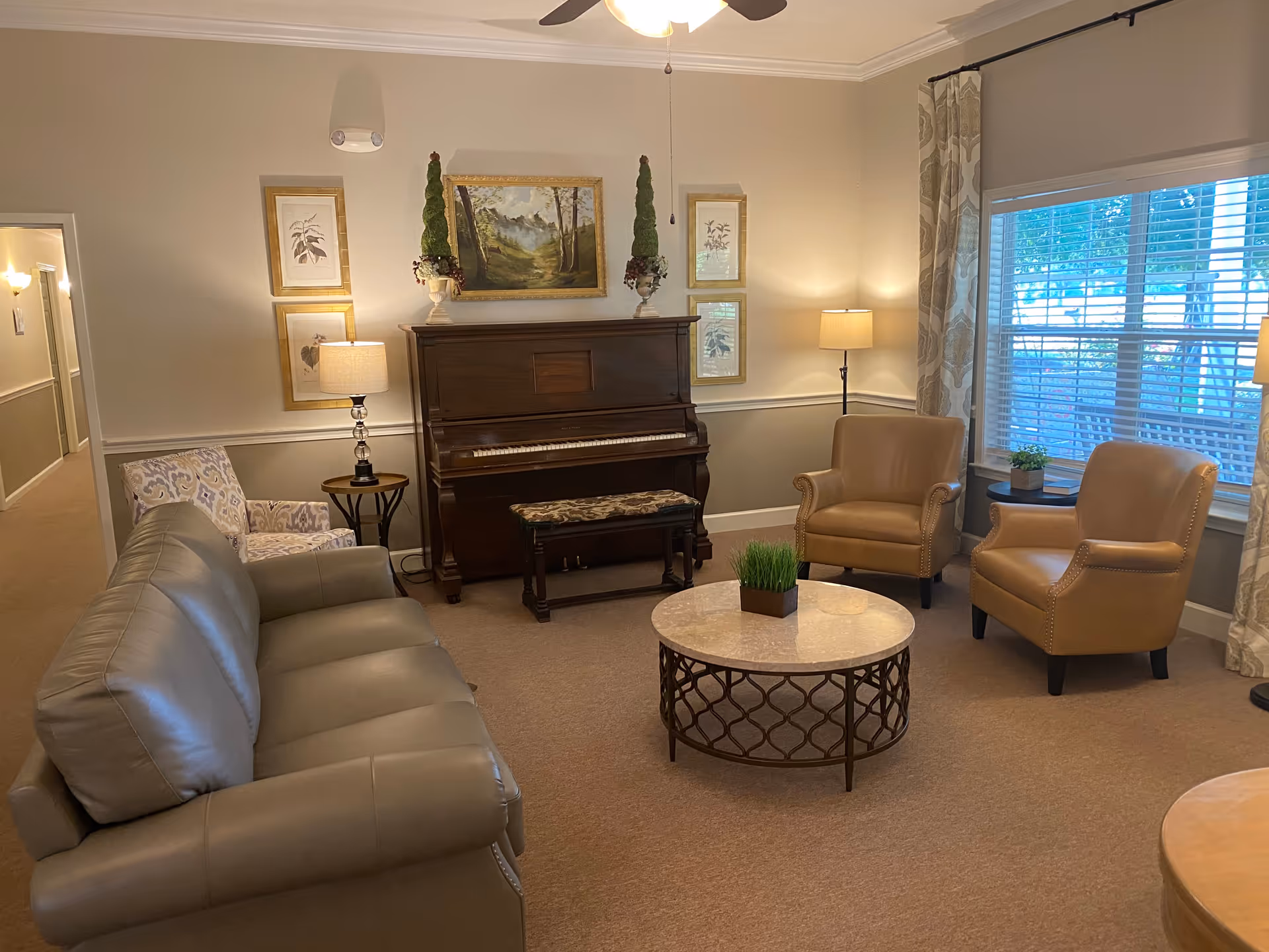 Cozy living room at Gardens of Eufaula with sofa, two armchairs, piano, and marble coffee table.