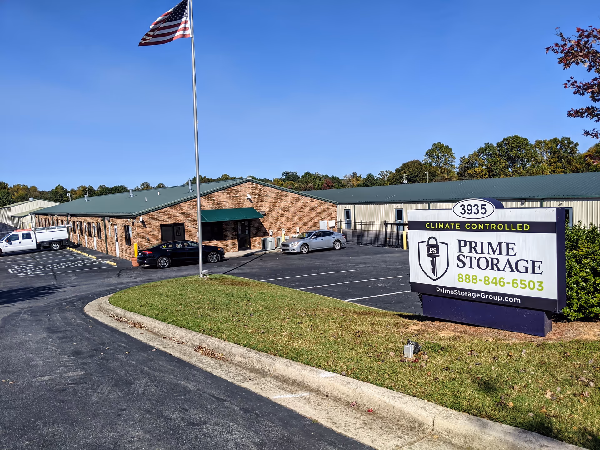 Exterior view of a Prime Storage facility with a flag, parking lot, and sign