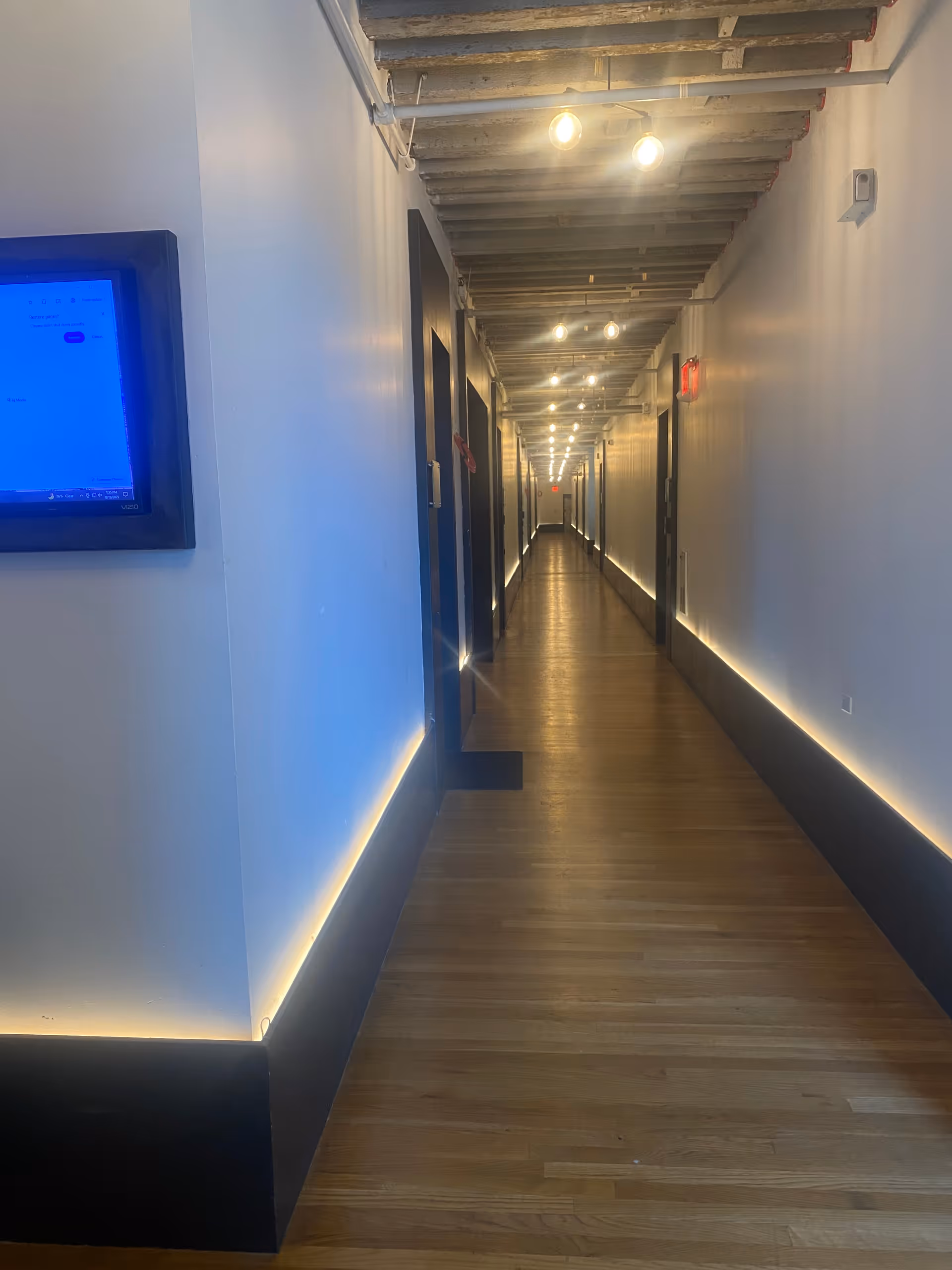 Long, well-lit corridor in a senior living facility with doors on each side.