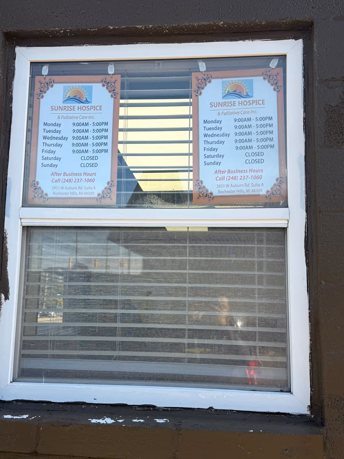 Two posted Sunrise Hospice signs displayed in a window of a building.