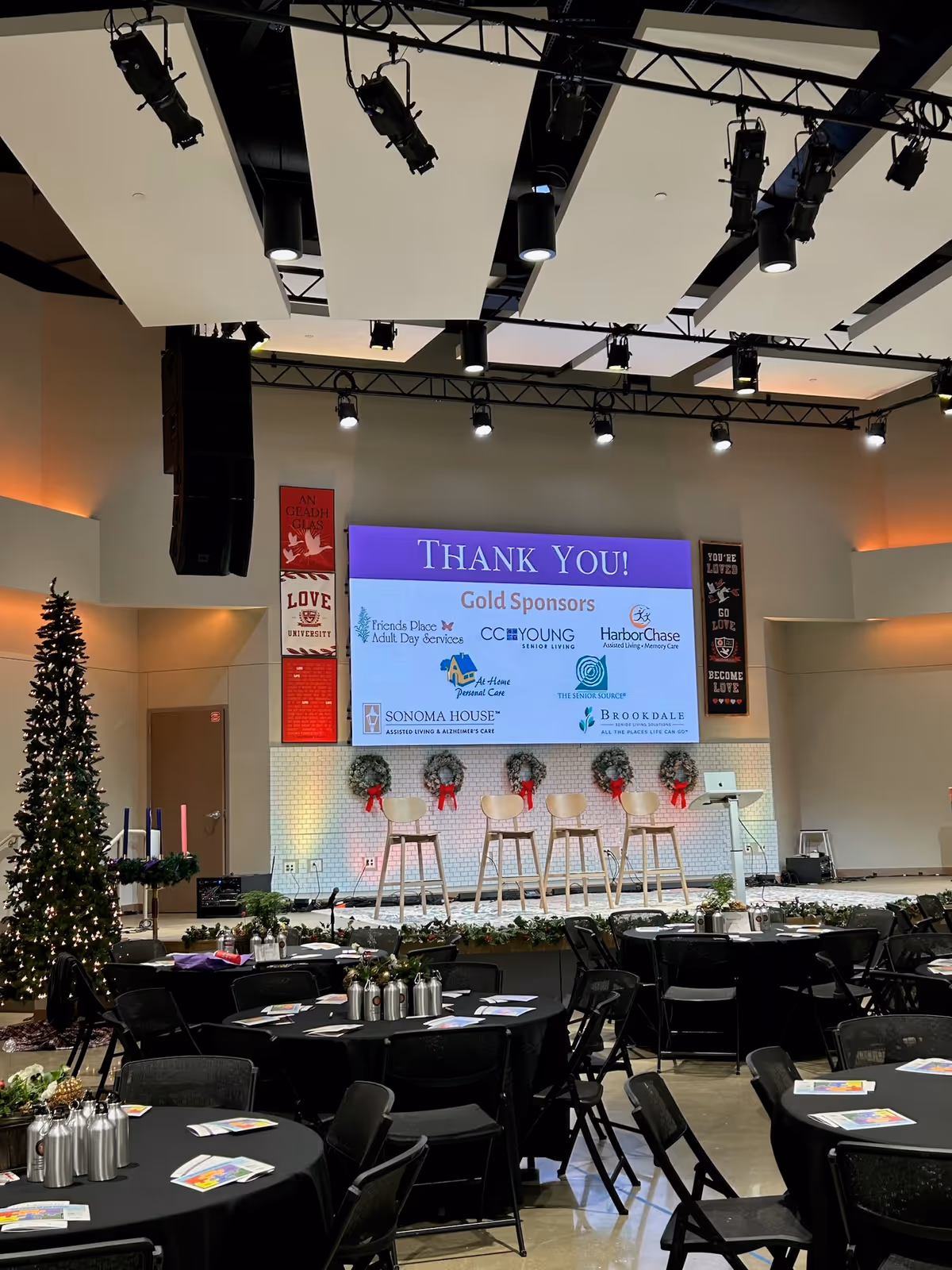 Stage with a 'Thank You!' display, round tables, and a Christmas tree.