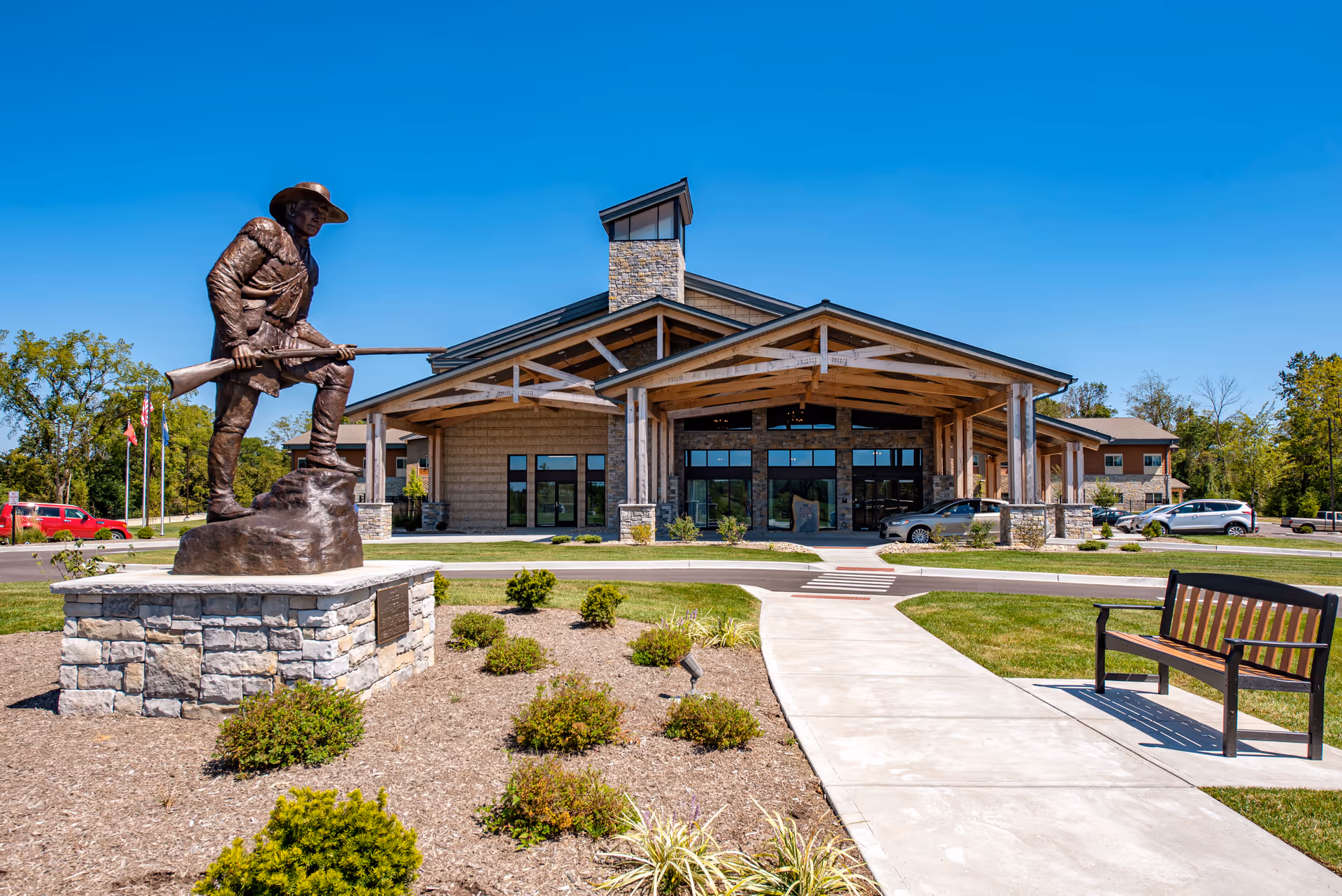 Front view of Boonespring Skilled Nursing Facility with statue, walkway, and bench.