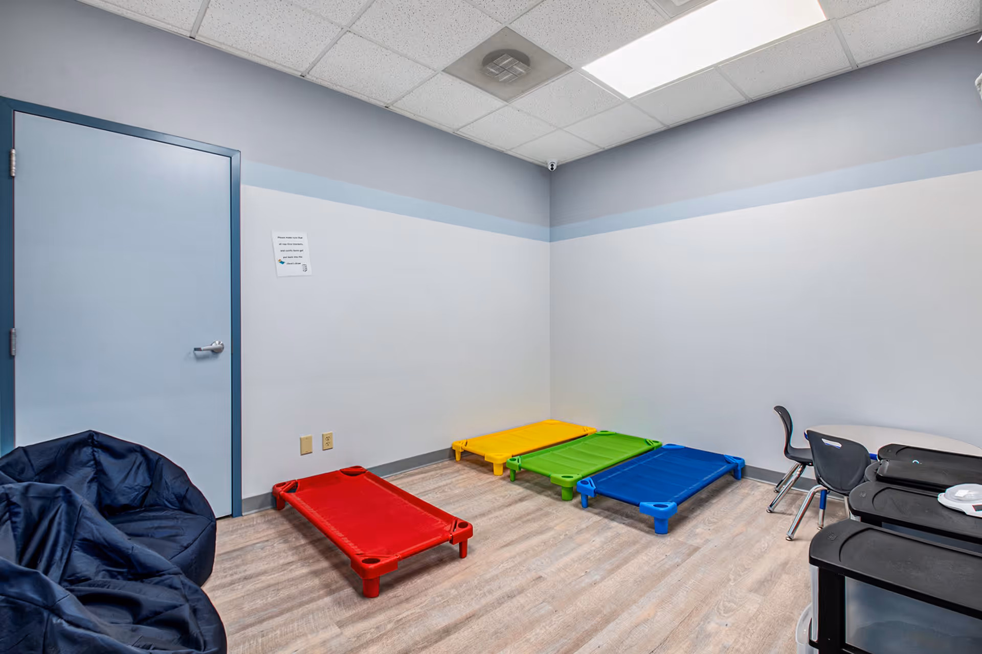 Indoor therapy play area with colorful balance platforms, bean-bag chairs, and a desk.