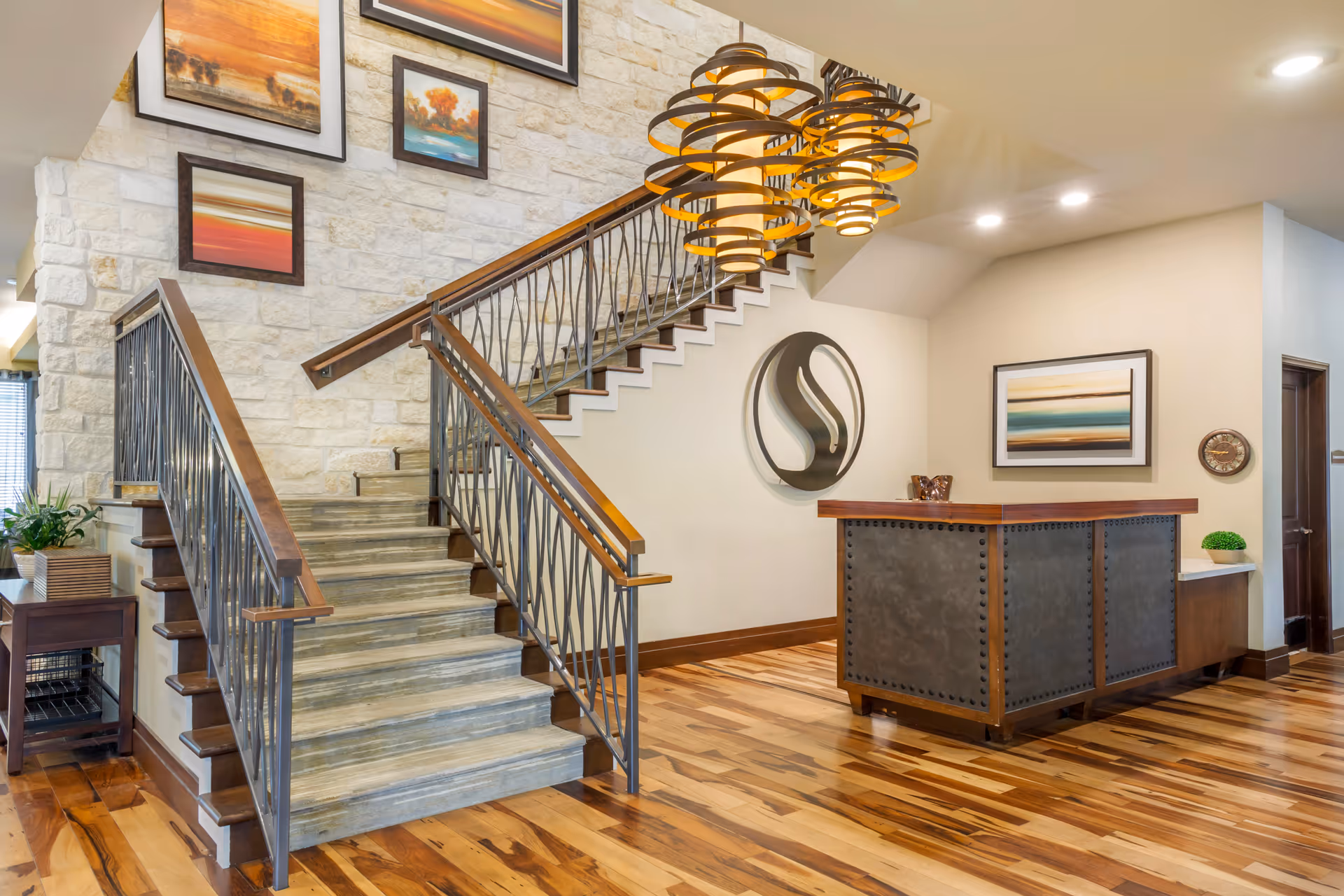 Contemporary senior living lobby featuring a grand staircase, reception desk, and wall art.