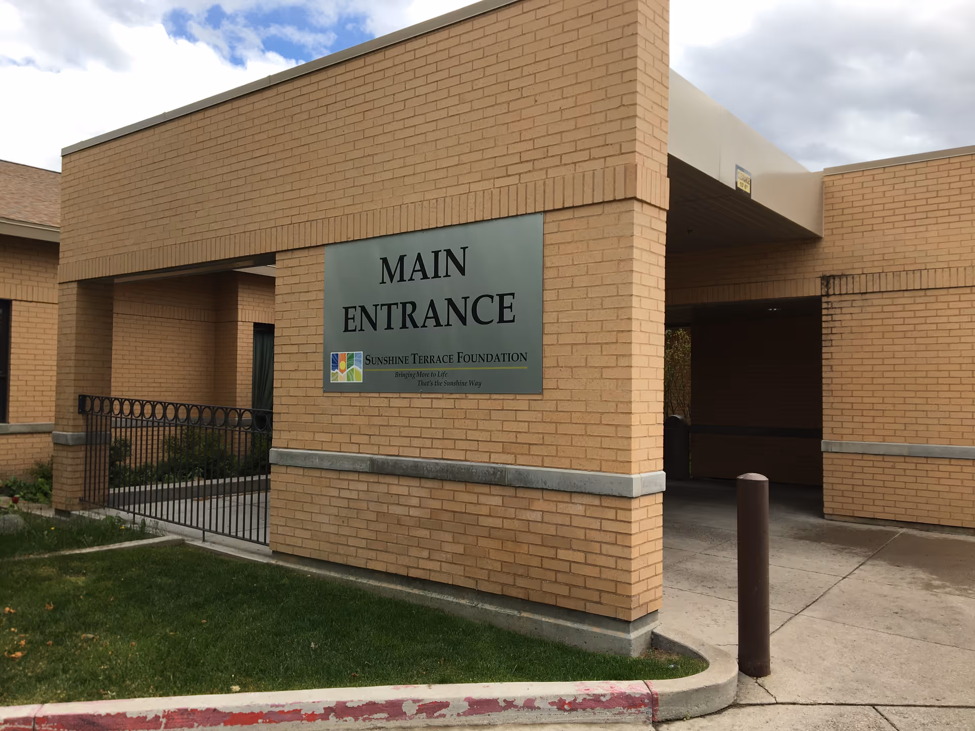 Brick building with a large Main Entrance sign and a covered entryway