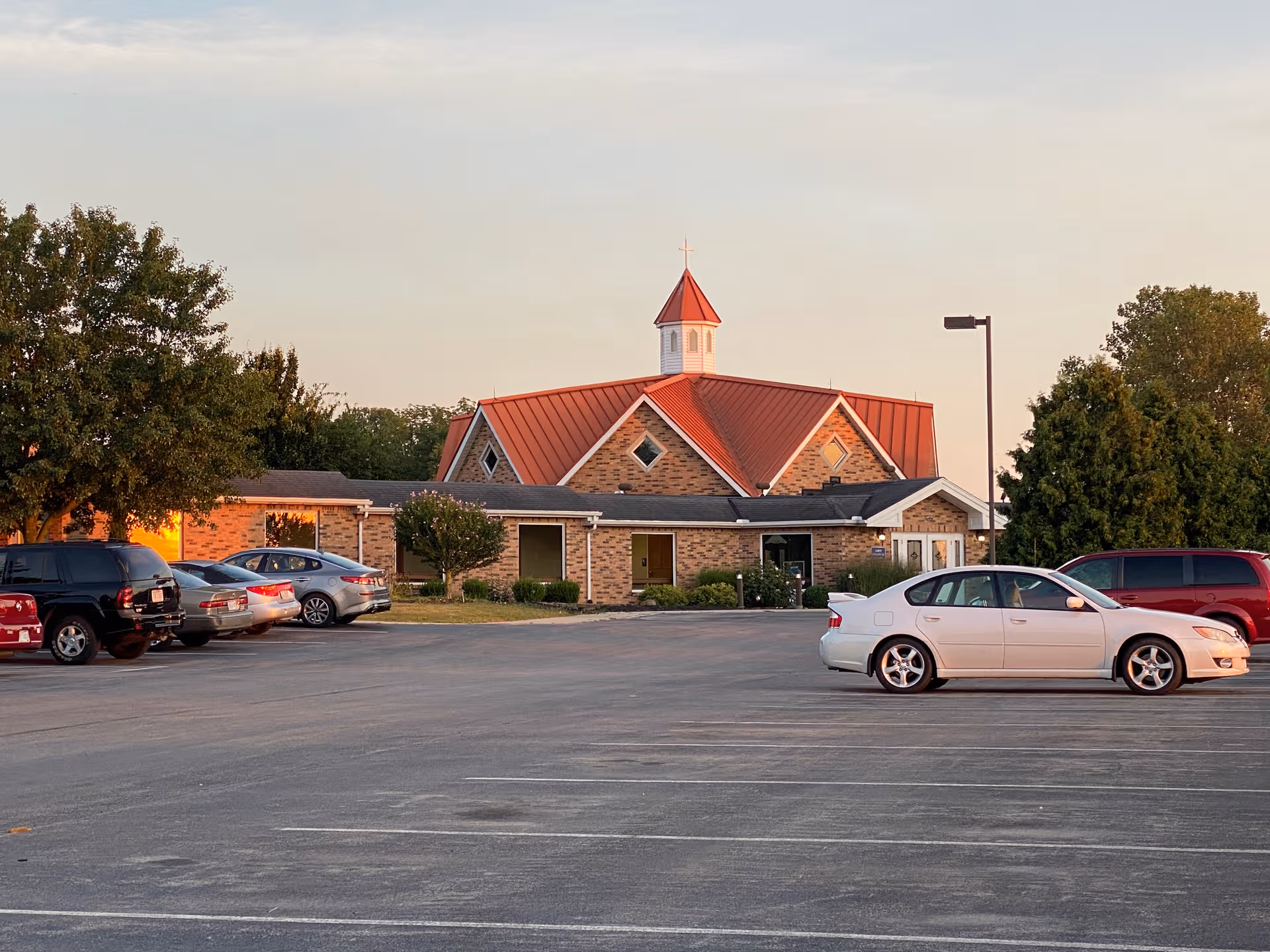 A brick Ohio Living Dorothy Love facility with red roof, cross-topped cupola, and parked cars.