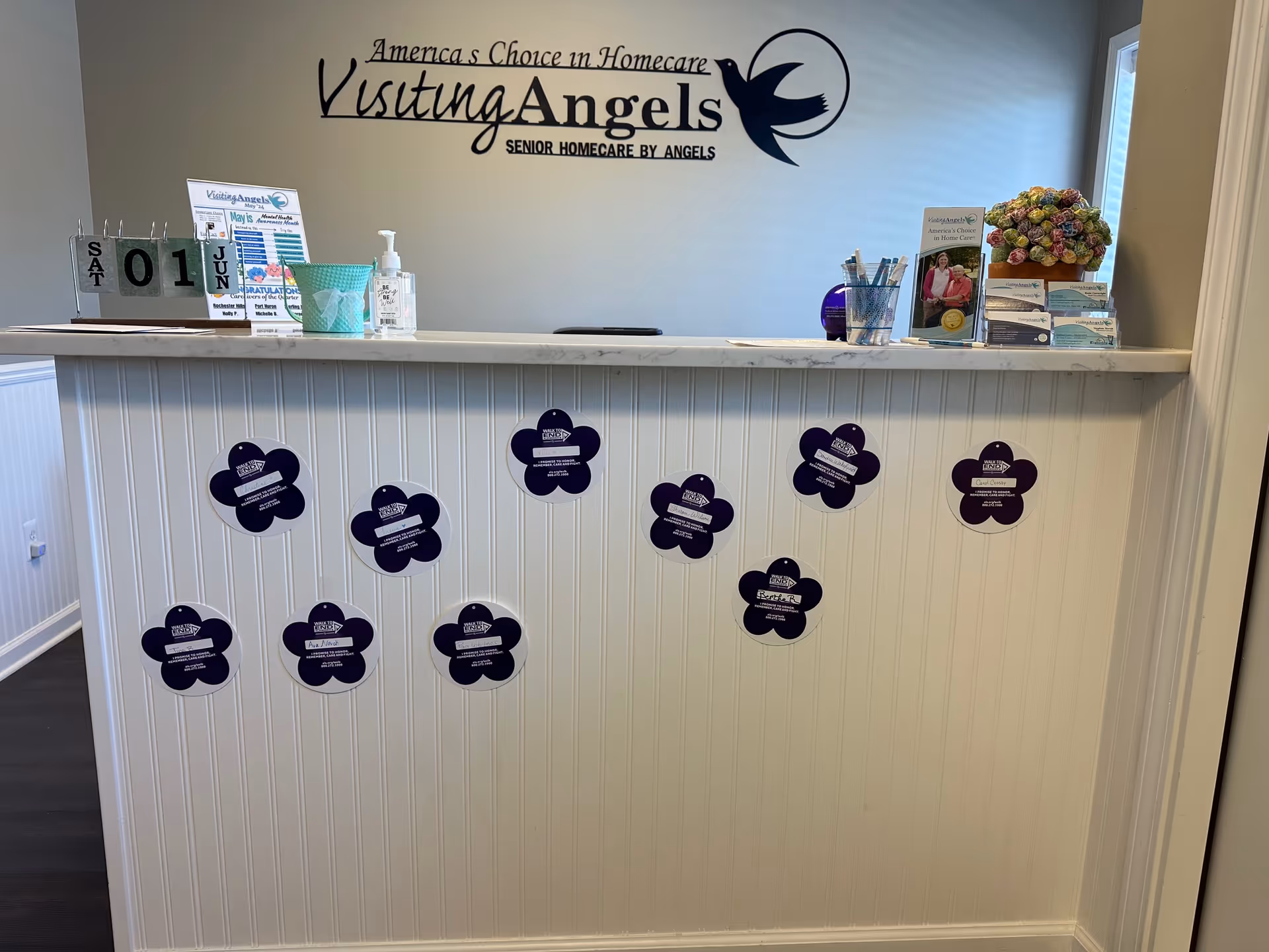 Reception counter at Visiting Angels Senior Home Care Rochester Hills, with brochures and purple flower decals.