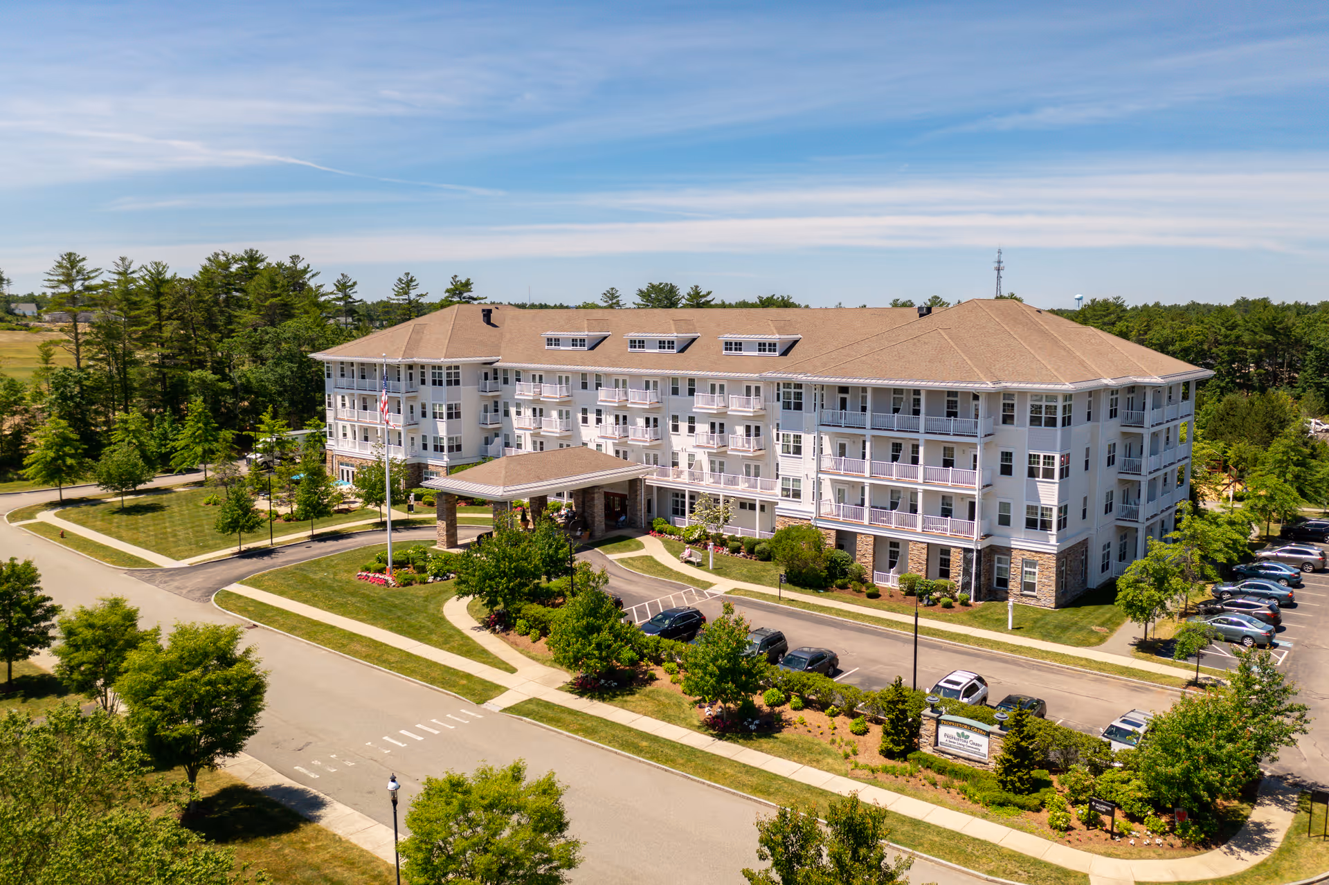 Village at Proprietors Green senior living building with balconies, entrance canopy, and surrounding parking.