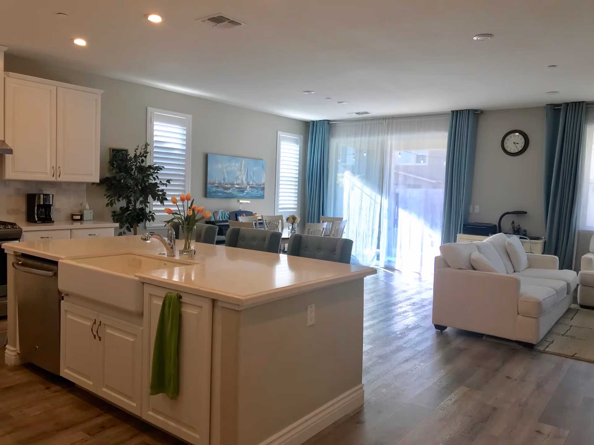 Open-concept kitchen and living area with white cabinetry, island, and blue-curtained windows.