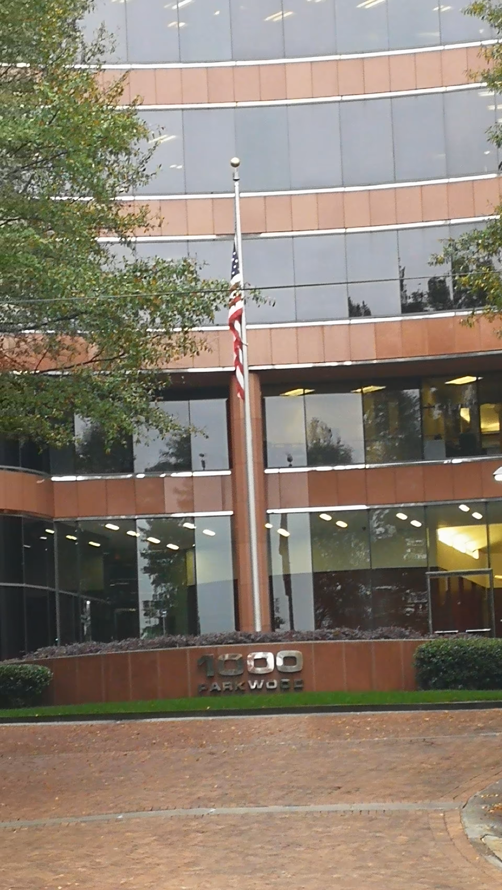 Exterior view of a glass-front building with an American flag and 1000 Parkwood signage.