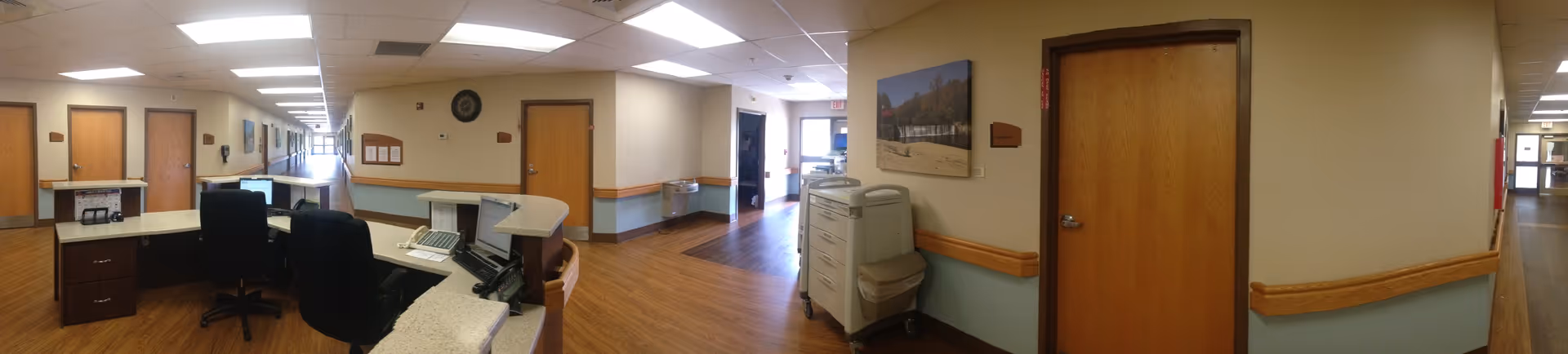Reception area with desks, computers, and a long hallway in a senior living facility.