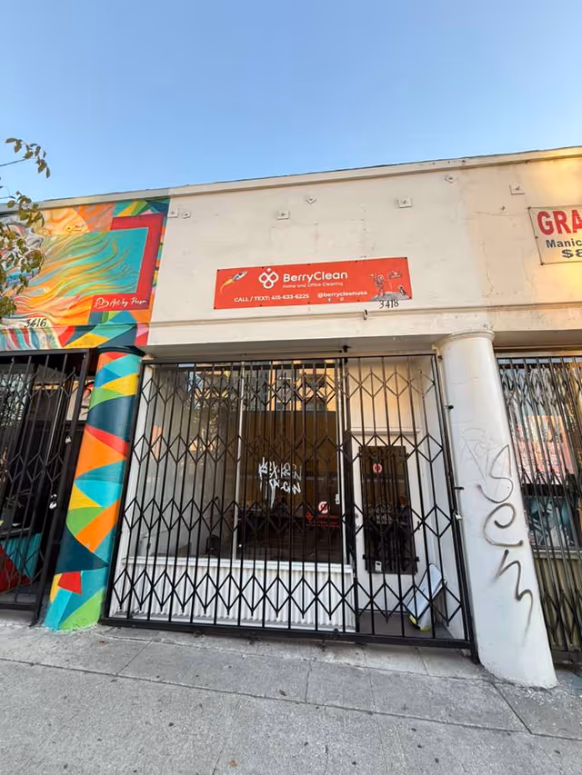 Wide storefront facade with a beige building, colorful mural column, and BerryClean sign.