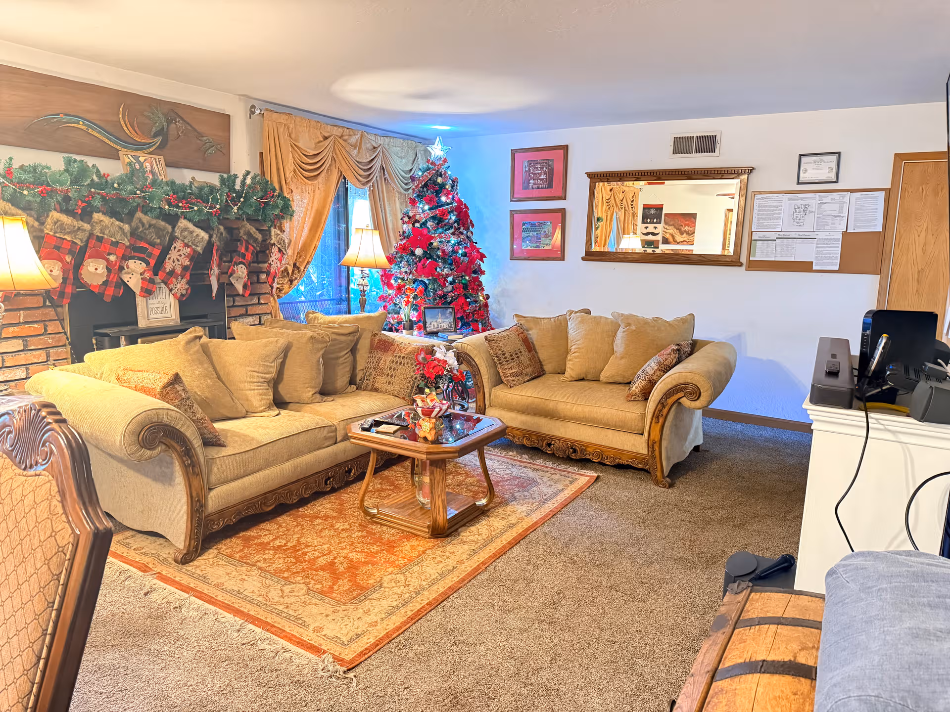 Cozy living room with a Christmas tree, sofas, a fireplace mantle, and festive decor.
