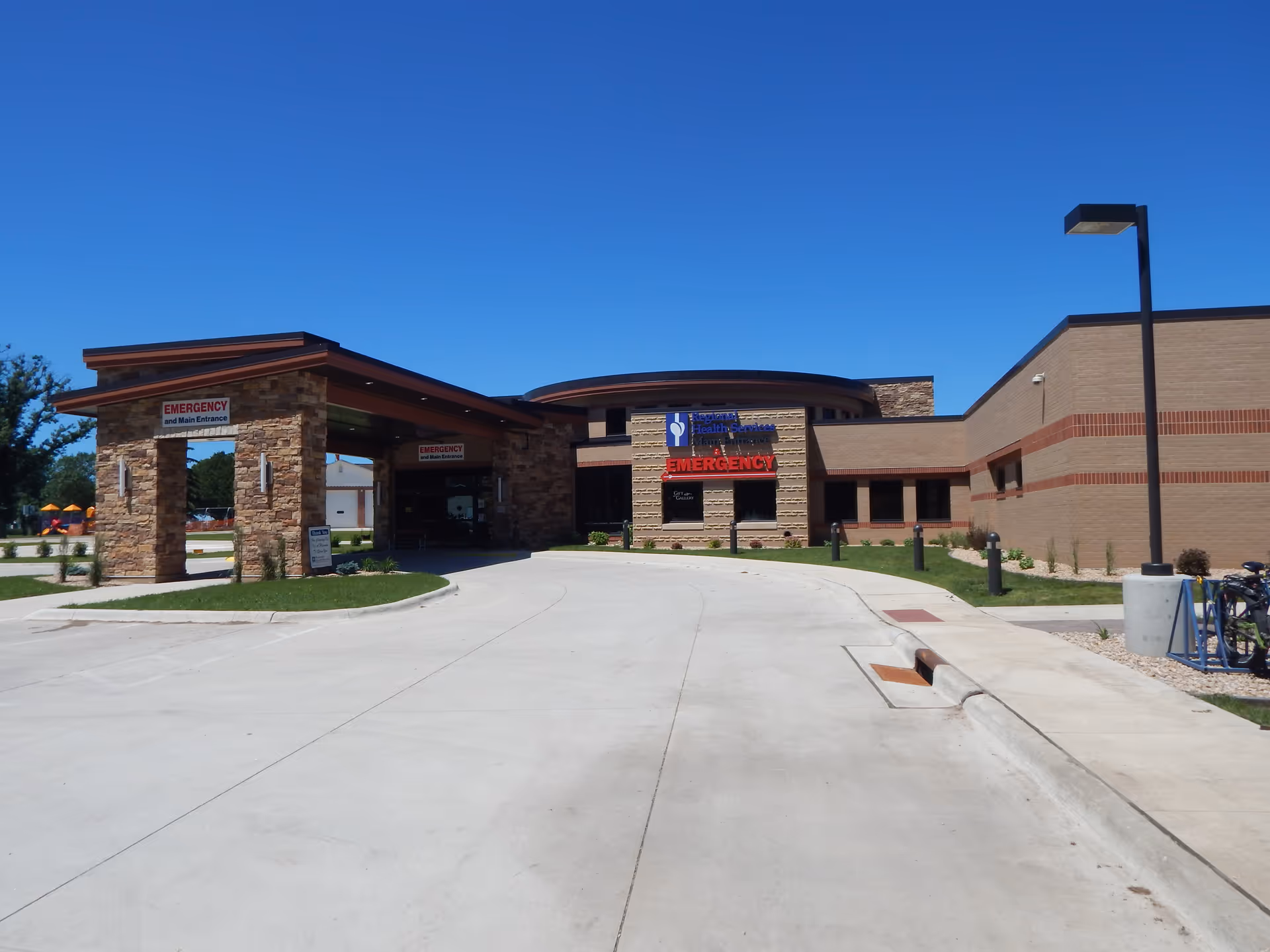 Exterior view of a modern medical facility with emergency entrance and curved driveway.