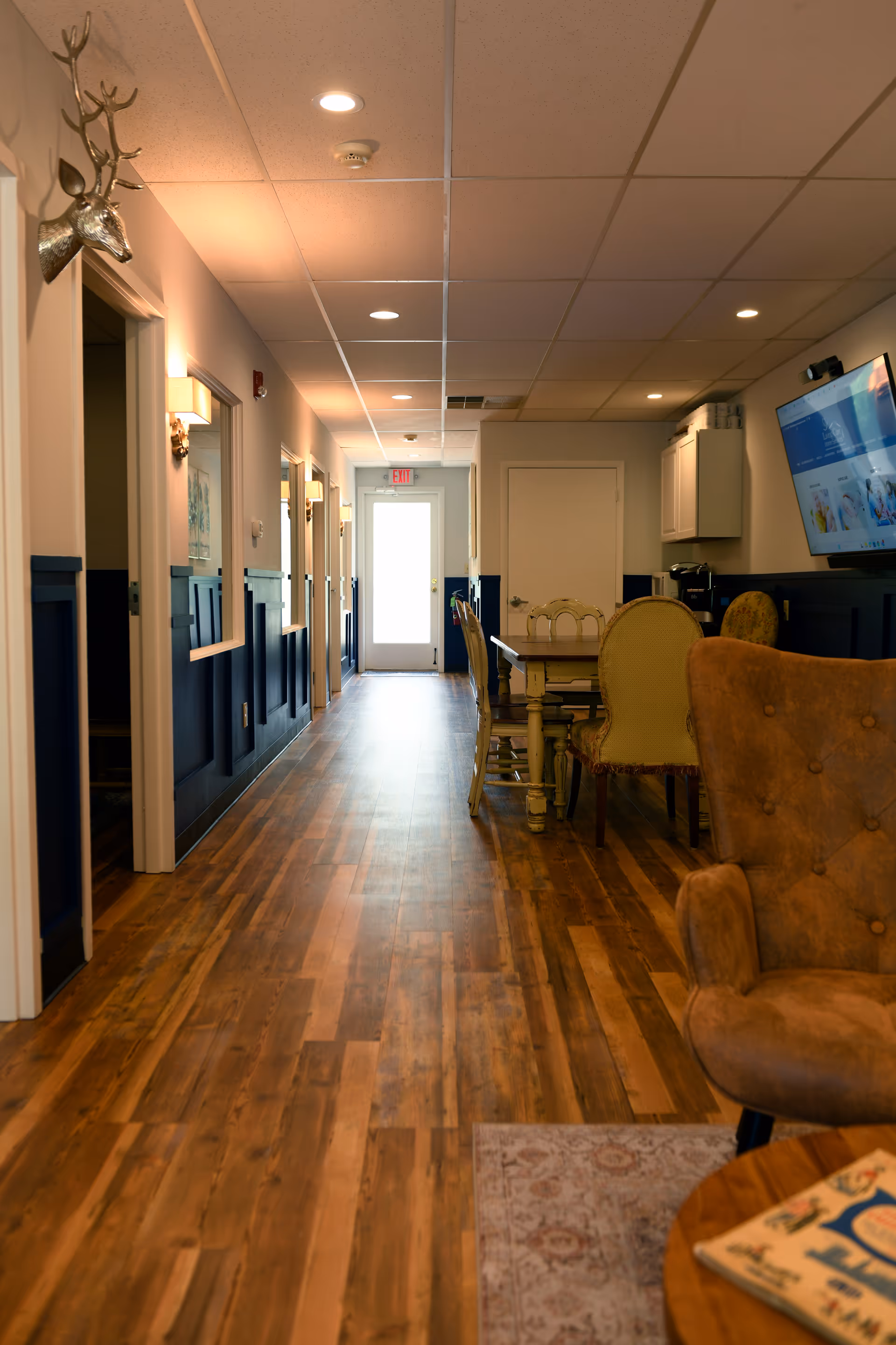 A long hallway inside a senior living facility with a dining area and mounted TV.
