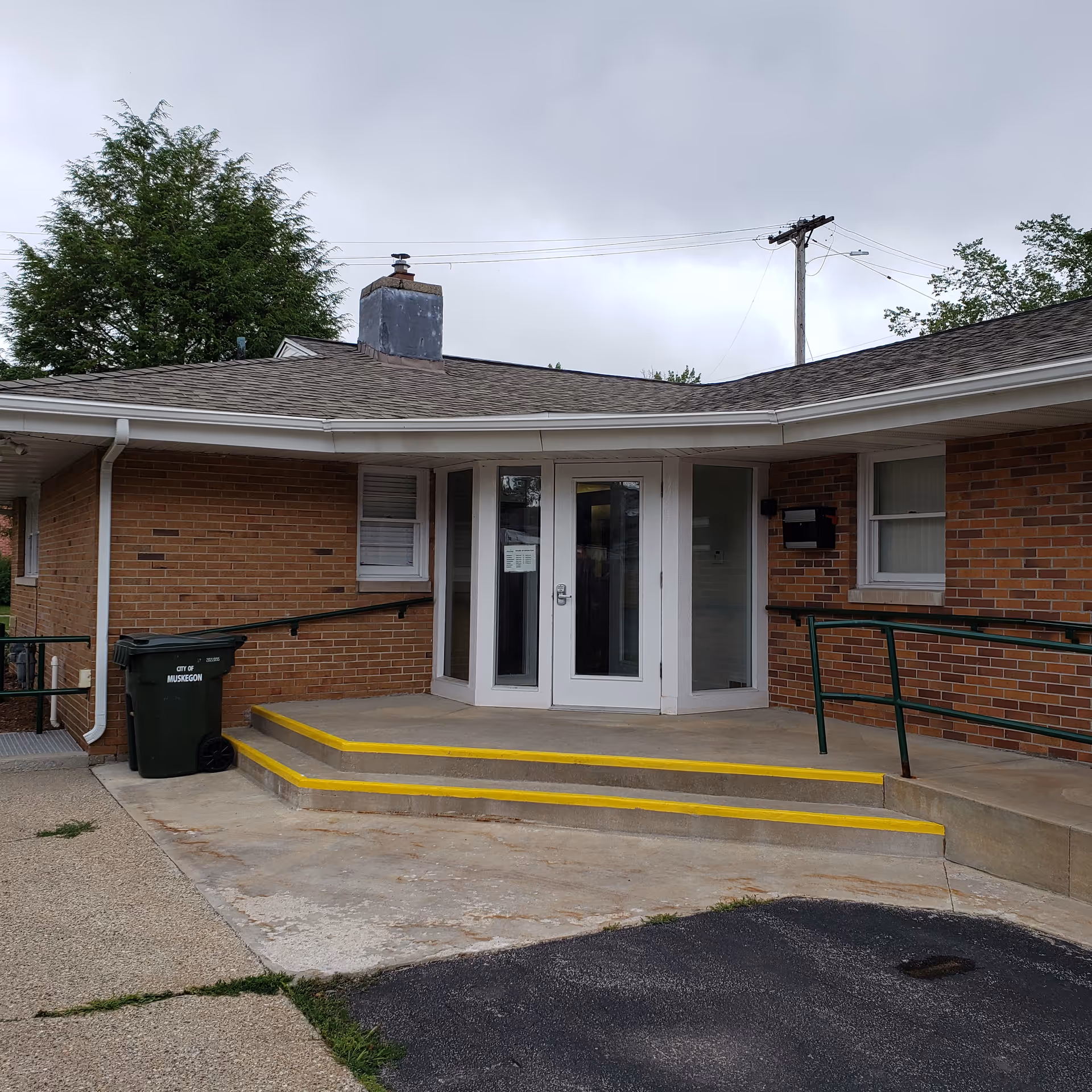 Brick facility entrance with glass doors and a ramp in front.