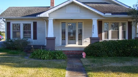 Front view of a single-story building with a covered entrance and manicured lawn.