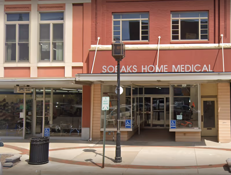 Red brick building storefront with Sobaks Home Medical sign, glass doors, and street lamp.