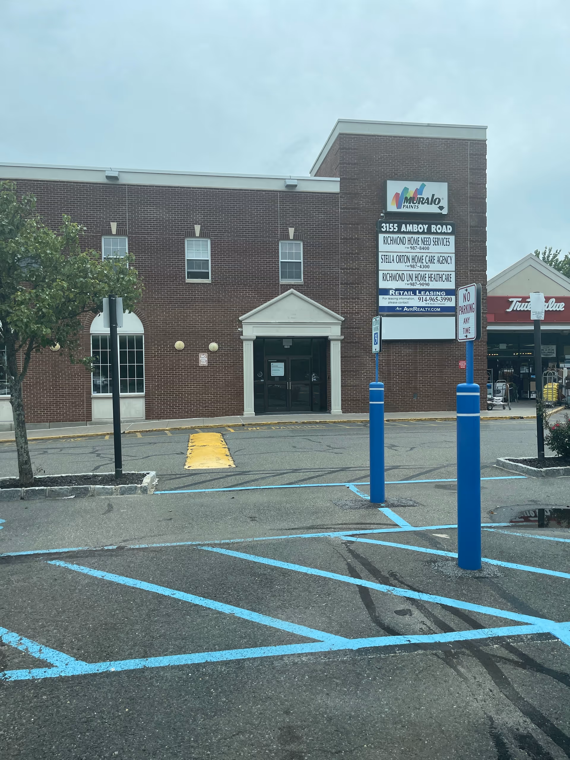 Brick senior living facility front with sign tower and blue parking markings.
