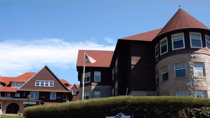 Exterior view of Beechwood senior living facility with red roof and flag.