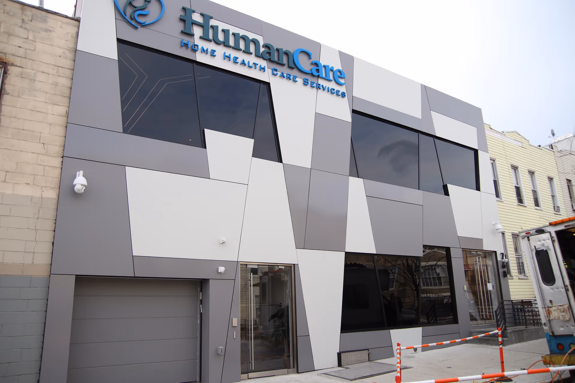 Exterior view of a modern geometric building facade with a 'HumanCare' sign.