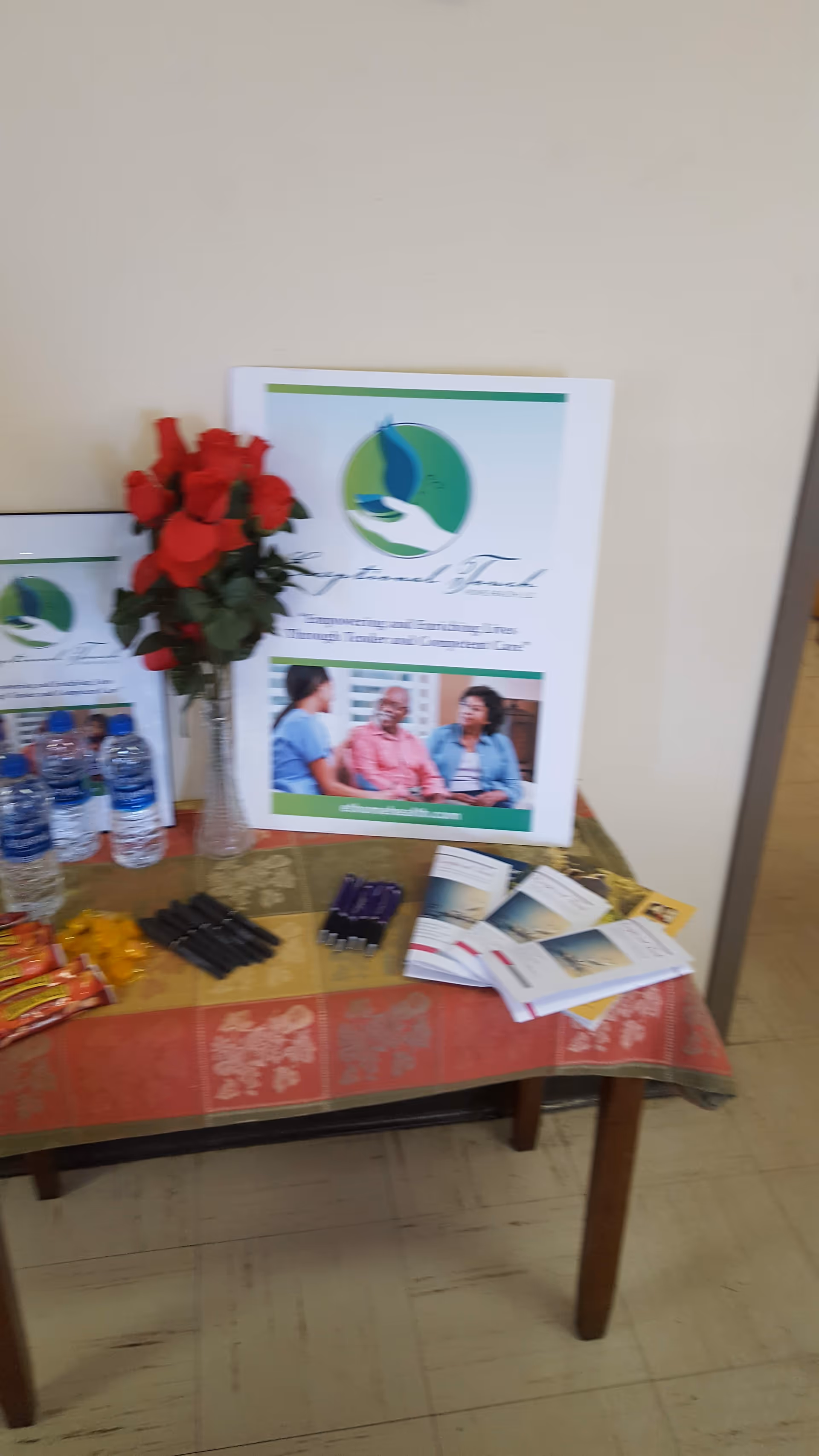 Promotional display with brochures and a bouquet of red roses on a table indoors.