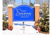Blue Dogwood Village sign on brick pillars in a snowy landscape at the facility entrance.