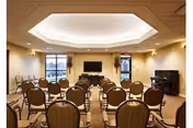 Spacious senior living common area with rows of chairs facing a wall-mounted TV