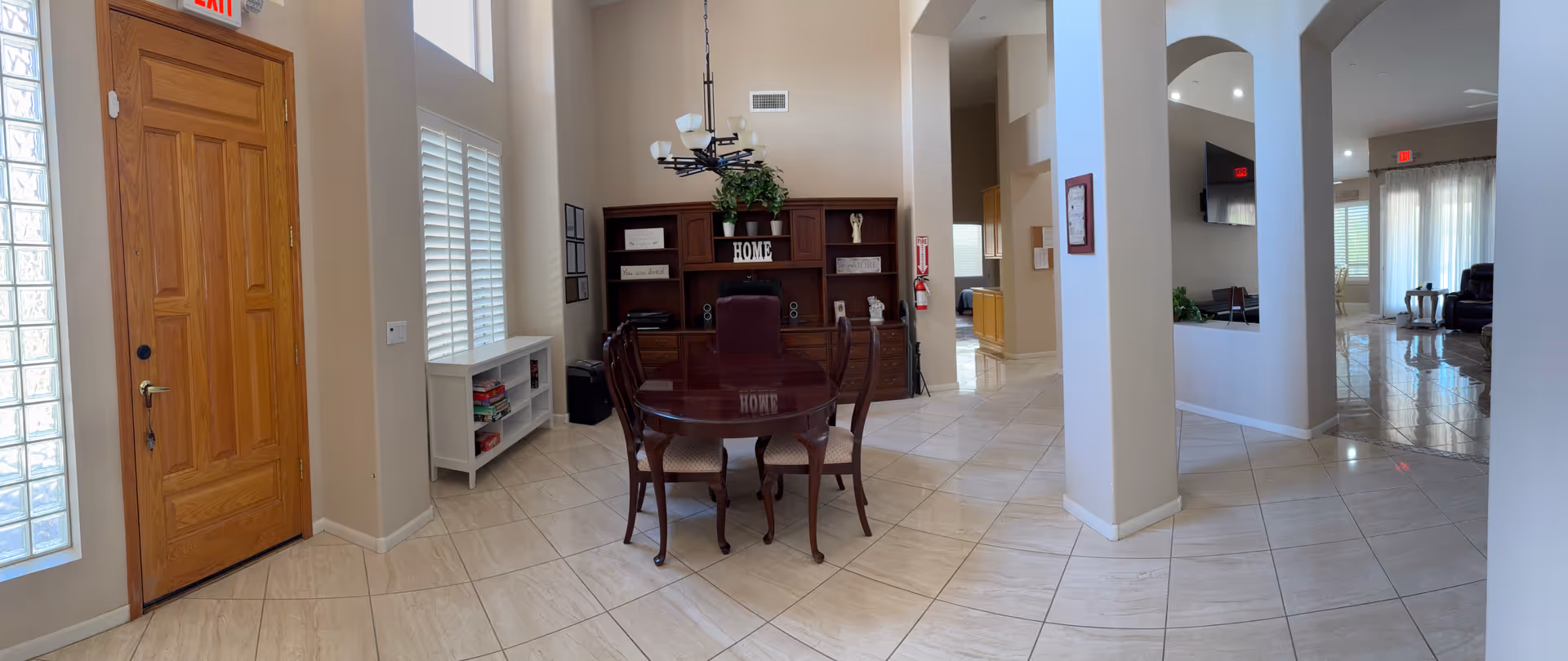 Interior common area of Holy Family Assisted Living with a round dining table and bookshelf.