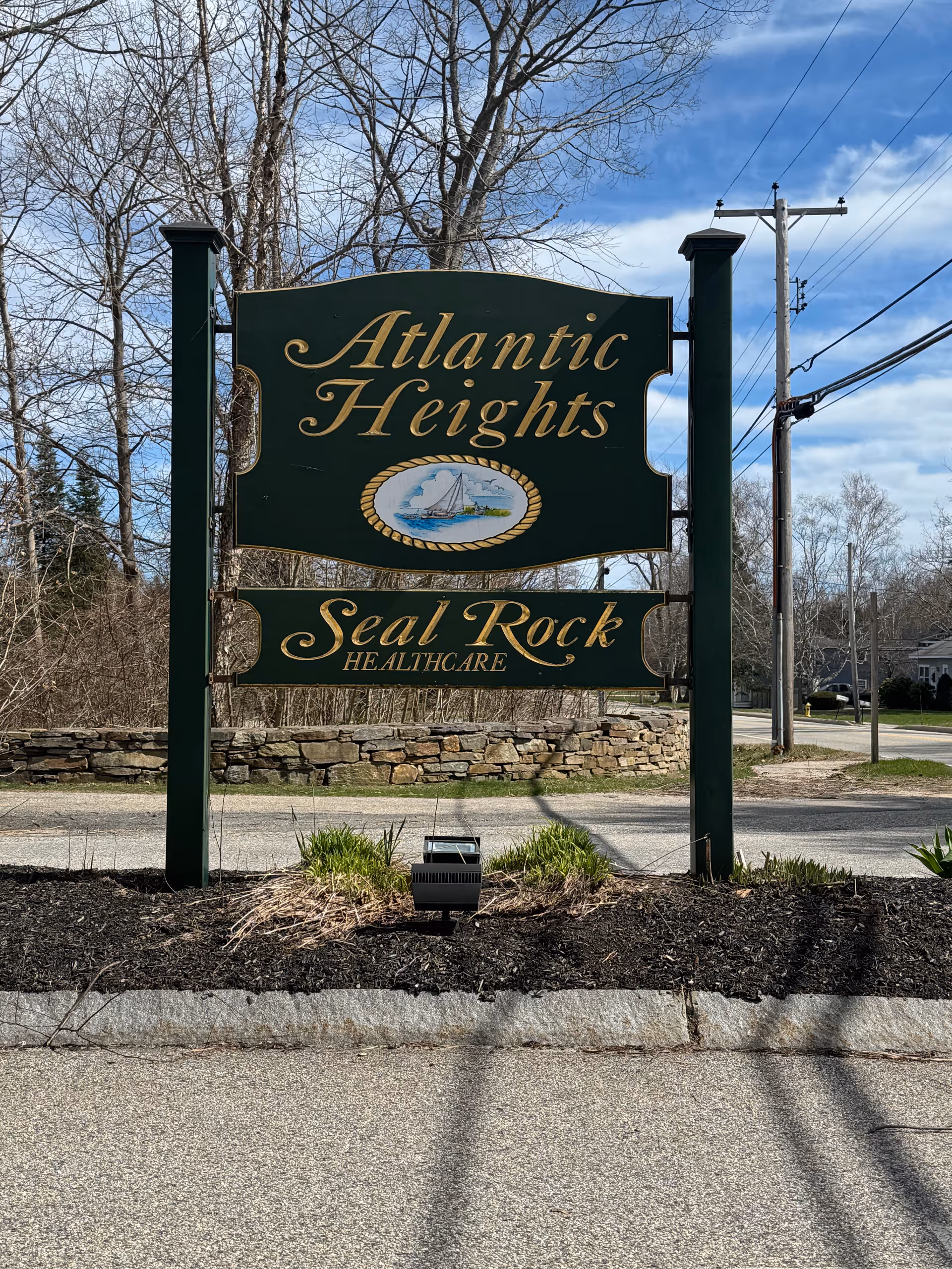 Dark green entrance sign reads Atlantic Heights and Seal Rock Healthcare against a blue sky.