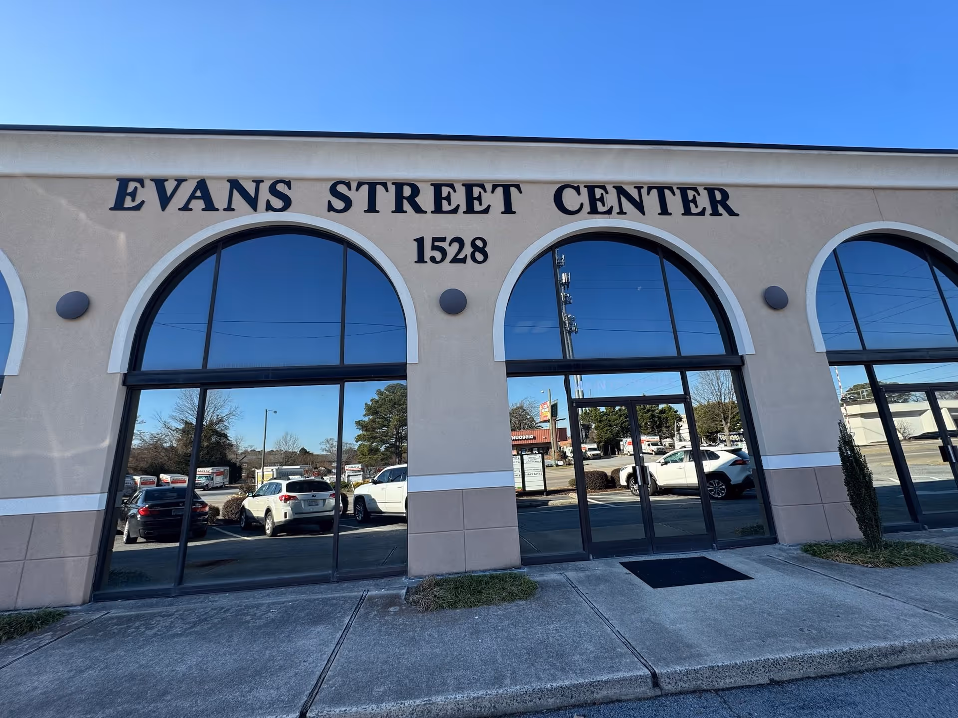 Exterior view of a building storefront with arched windows and Evans Street Center sign.