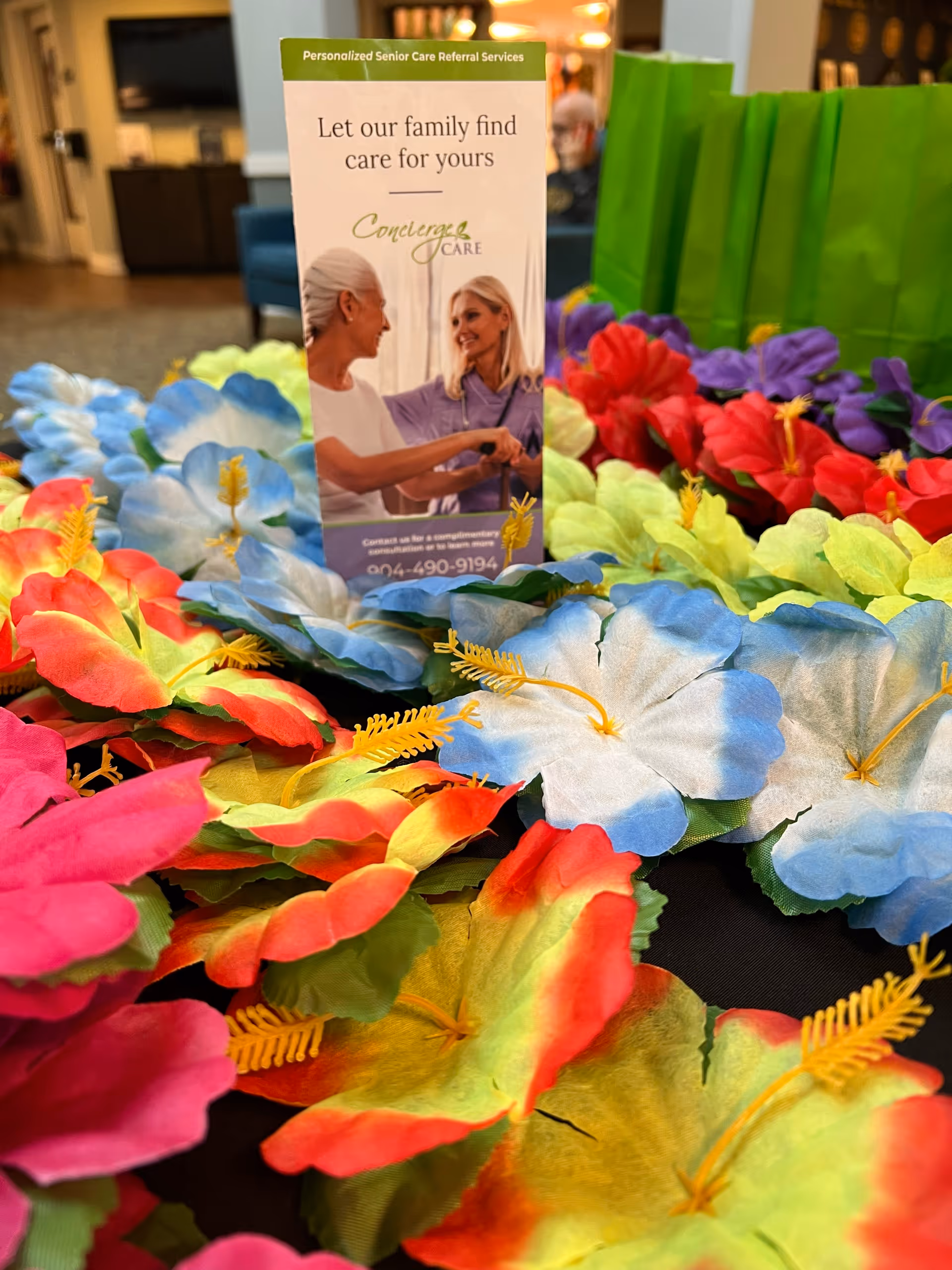Lobby display with vivid artificial flowers surrounding a Concierge Care brochure.