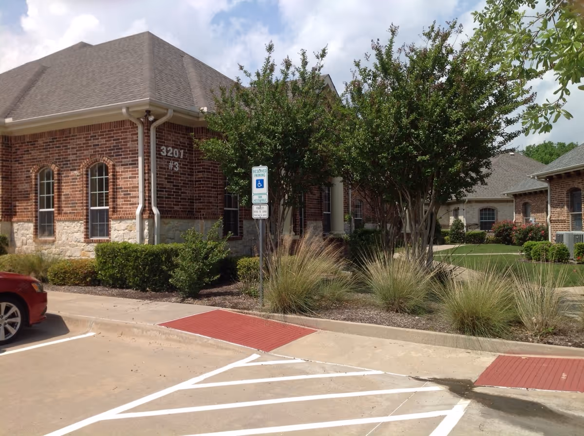 Brick senior living facility exterior with landscaped entrance and a wheelchair parking sign