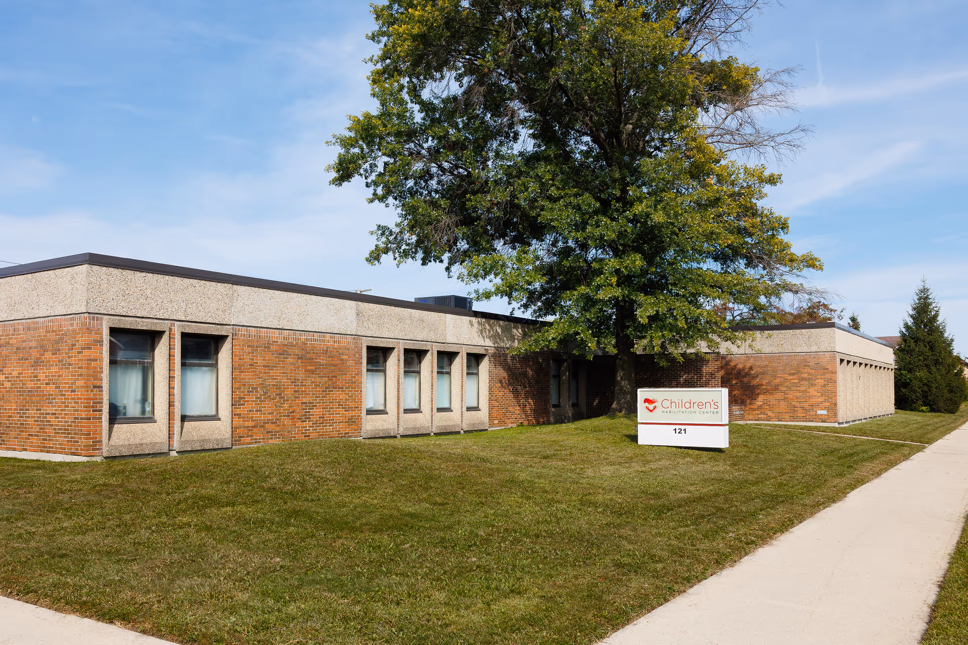 Exterior view of a brick facility with a lawn and a Children's Habilitation Center sign.