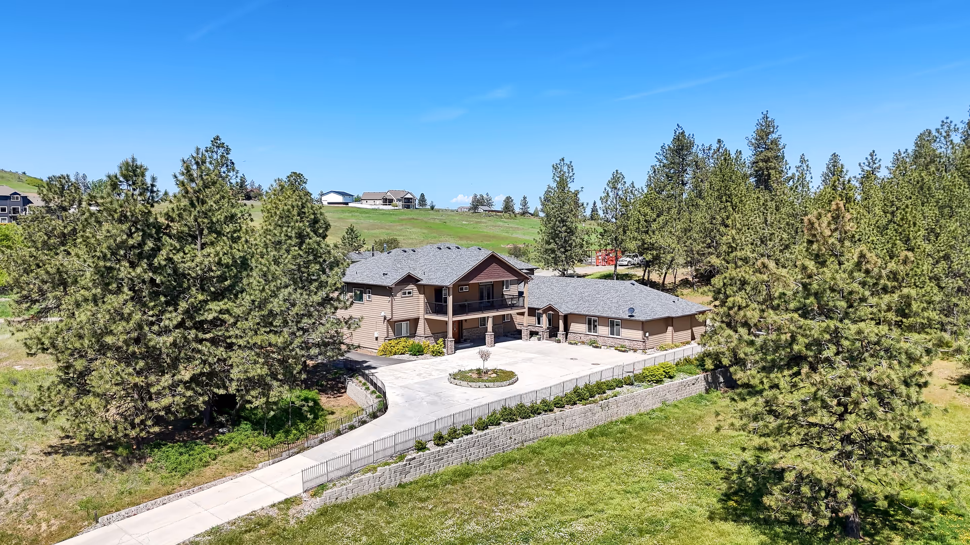 Exterior view of The Grove AFH North Spokane, beige building with circular driveway.