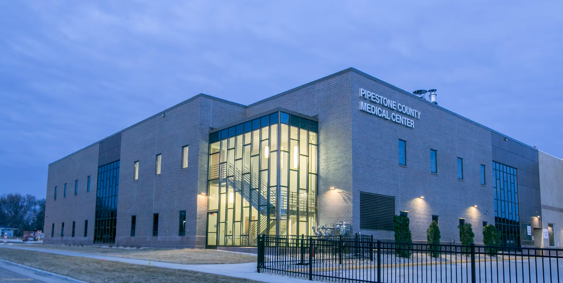 Exterior view of Pipestone County Medical Center building with glass entrance at dusk